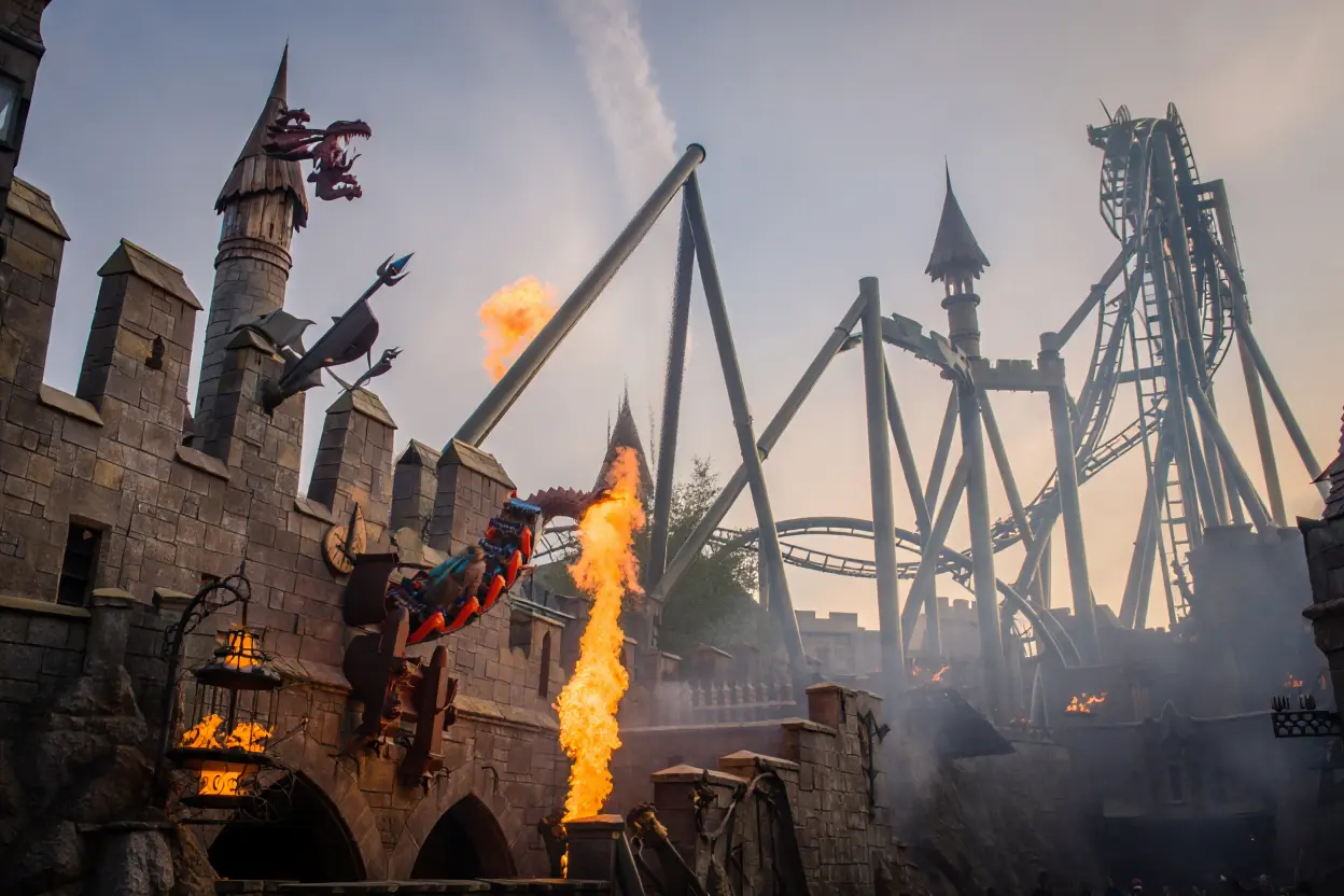 Montagnes russes autour d'un château avec dragons et flammes.